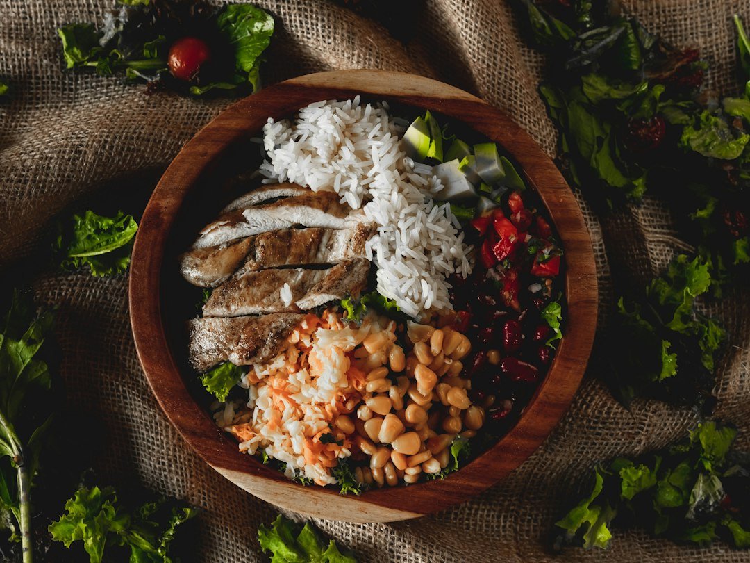 A wooden bowl filled with chicken, rice, and beans