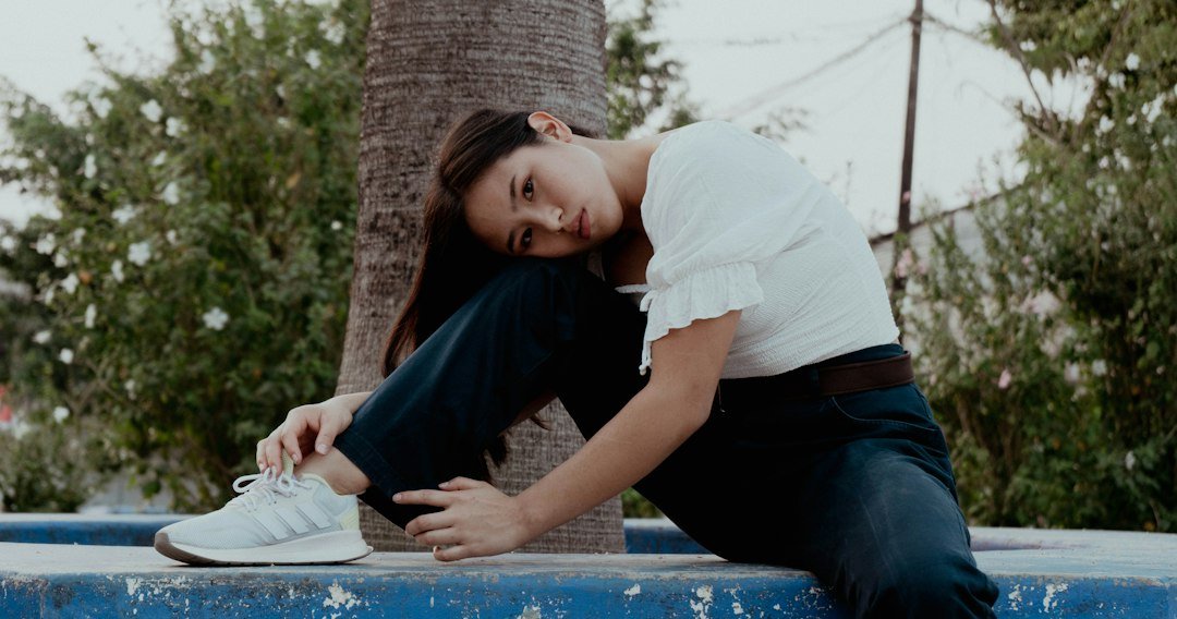 A woman is sitting on a ledge with her feet on the ground